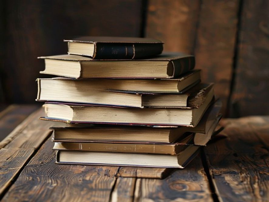 A stack of books and a journal on a wooden table, suggesting a season of study and reflection during a difficult time.